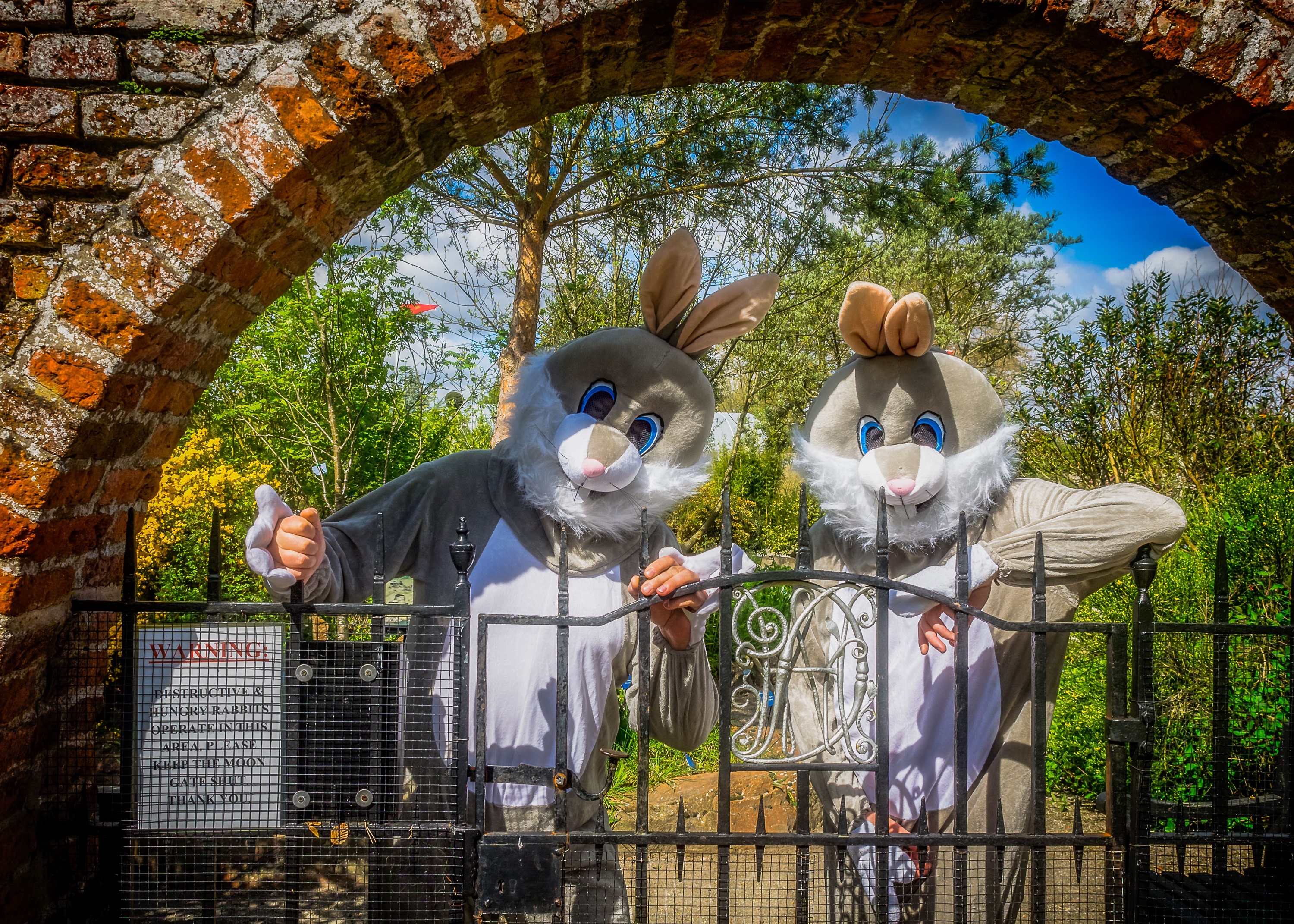 Two people dressed as Easter bunnies at the gates of Lullingstone Castle World Garden