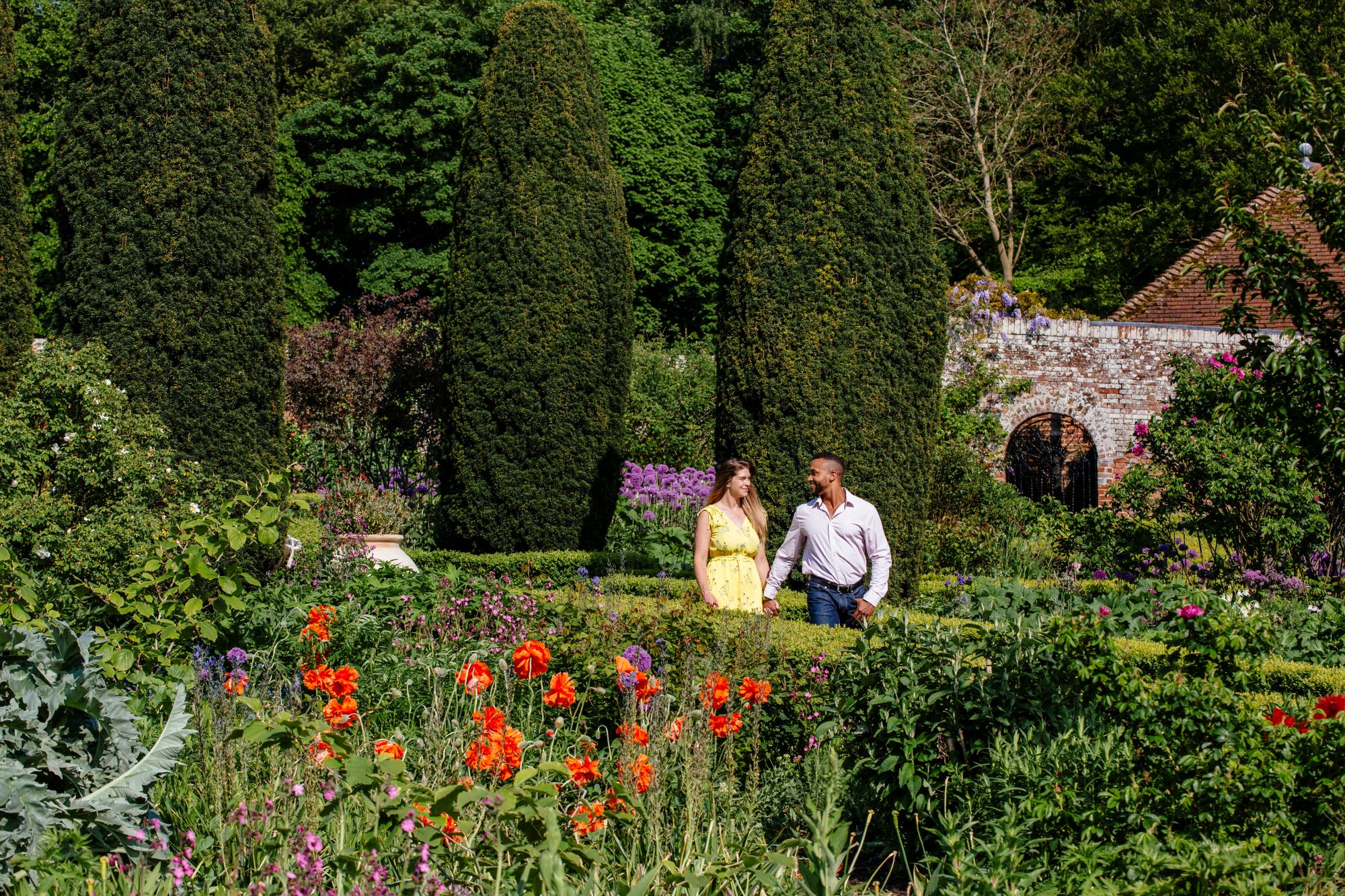 Couple walking hand in hand through the gardens of Leeds Castle in summer