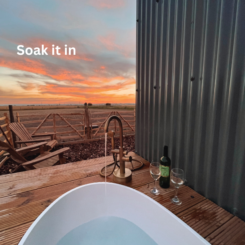 Outside bath, bottle of wine, two glasses and a sunset over Romney Marsh fields