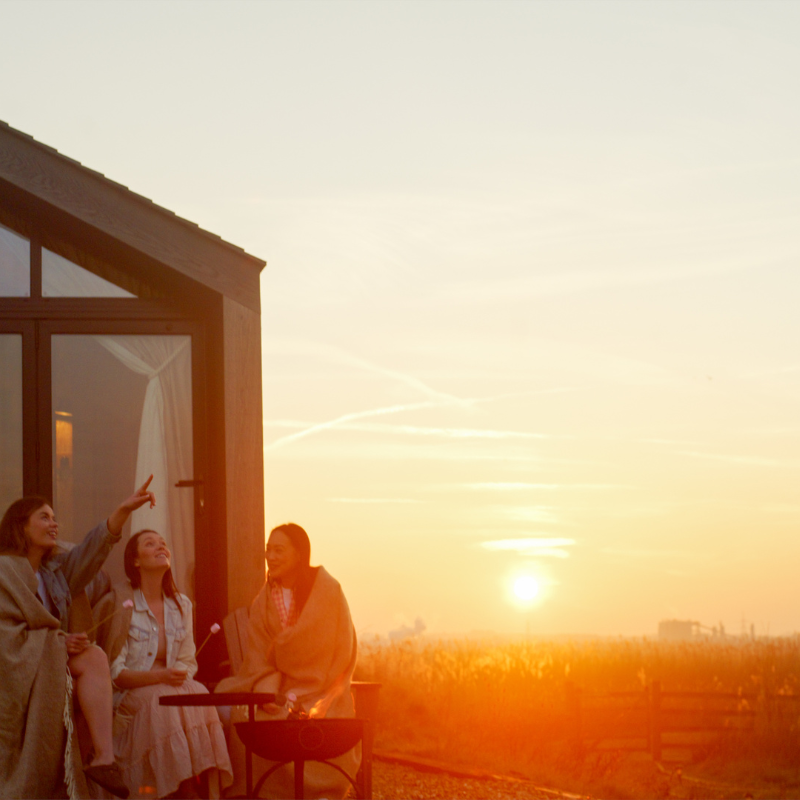 Group of three women outside a glamping pod at sunset in Sheppey