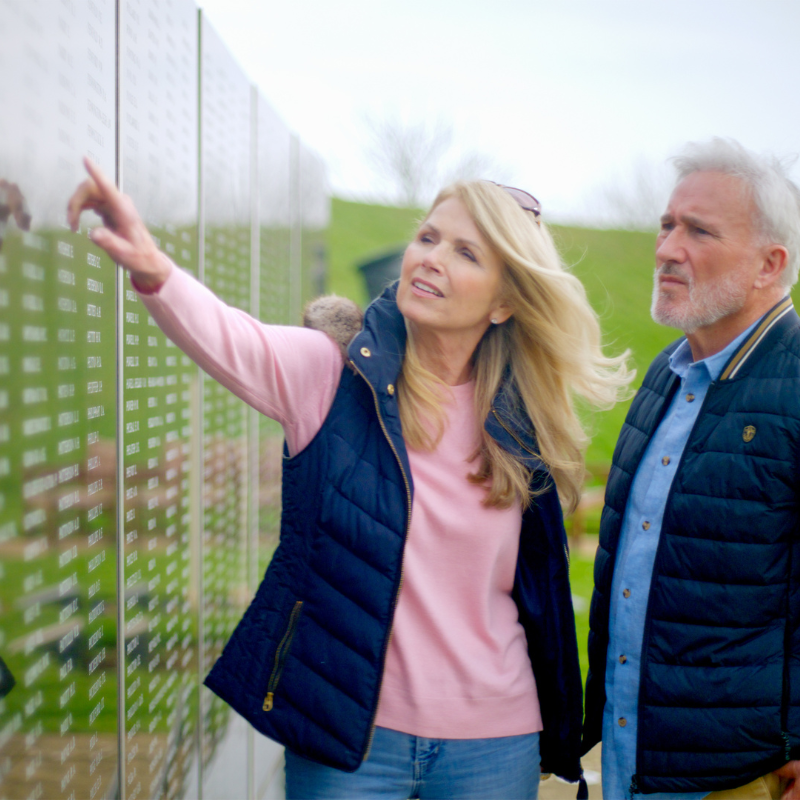 Couple pointing at names on The Wall at Battle of Britain memorial