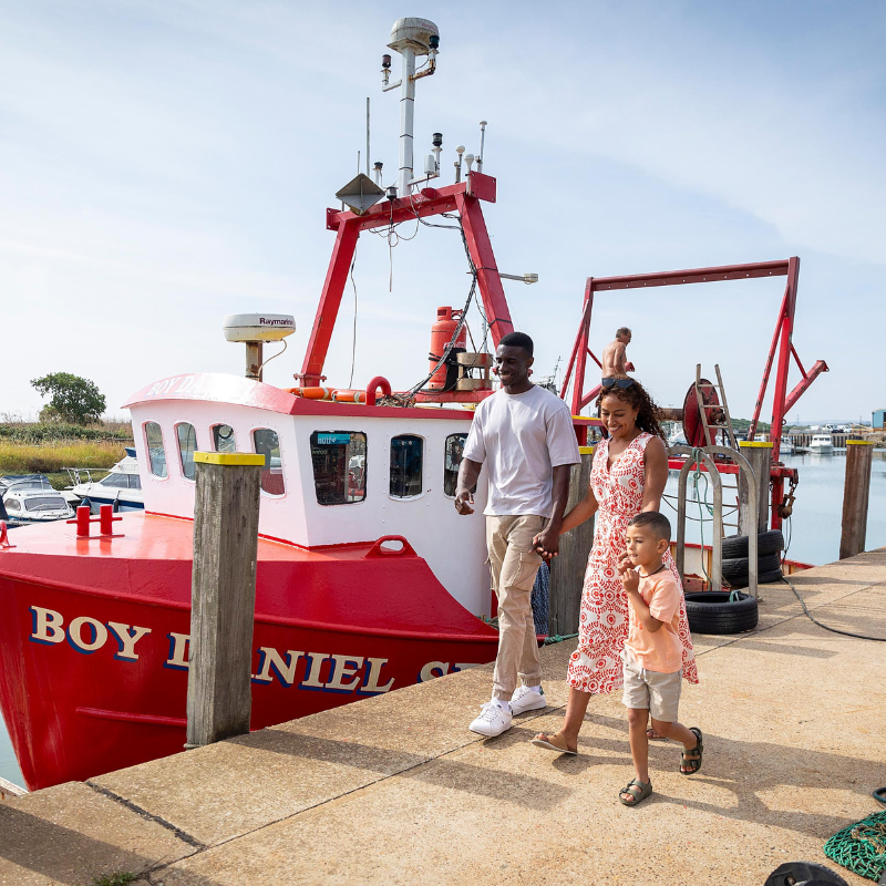 Family walking past boat at Queenborough Harbour