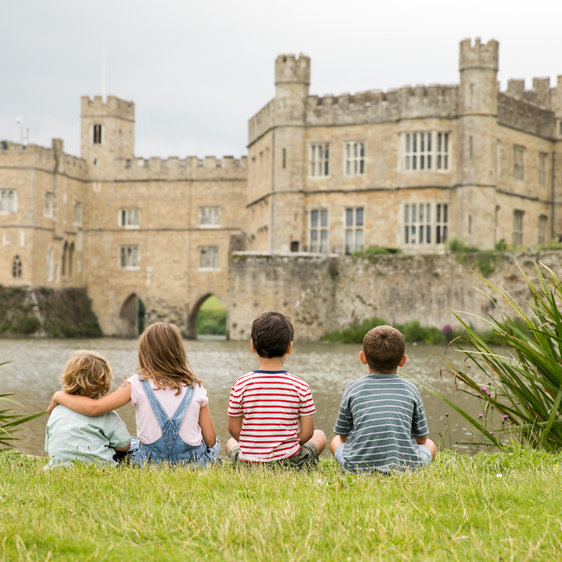 Children sat by the moat opposite Leeds Castle