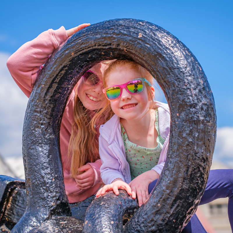 Two children peering through the anchor at the Historic Dockyard Chahtam
