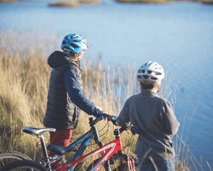 Two people standing next to bikes looking out over water